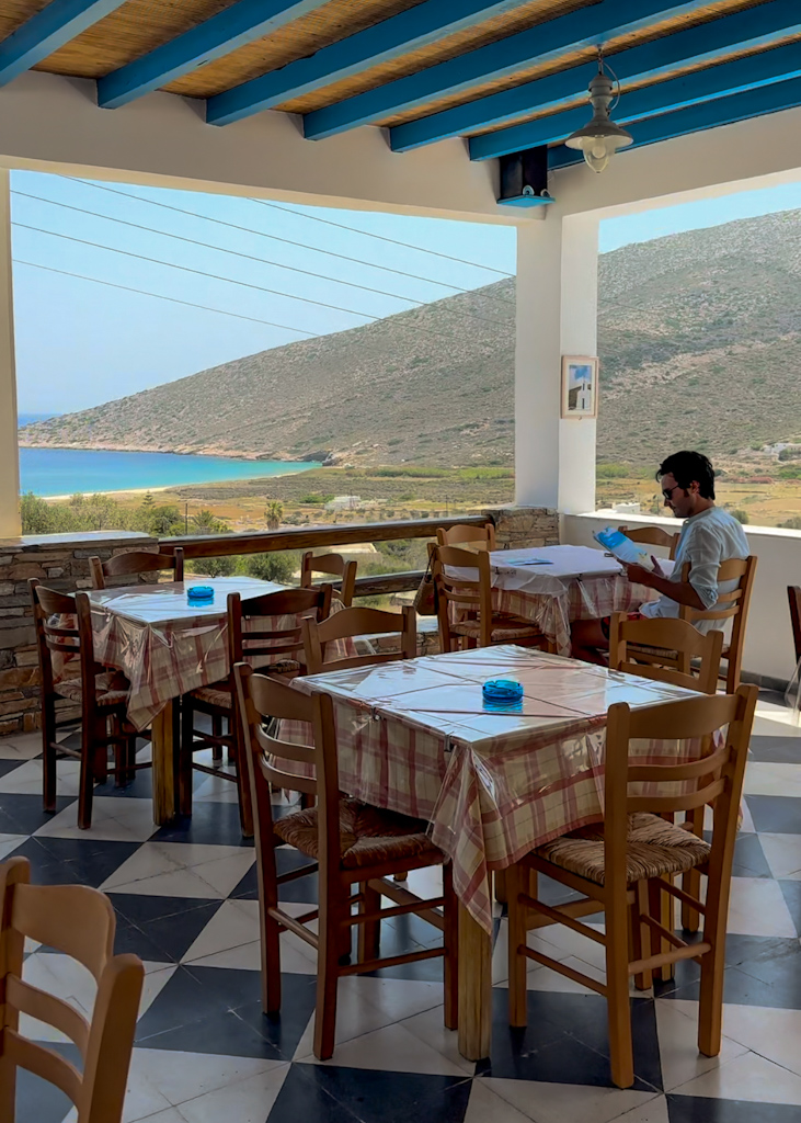 Ragazzo seduto al tavolo di un ristorante vista mare a Ios in Grecia