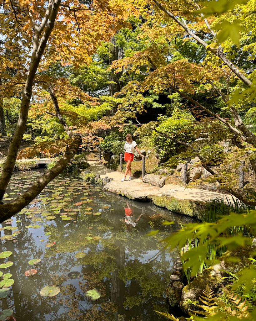 Ragazza in riva al laghetto pieno di carpe a Kyoto nel Tenjyuan Garden